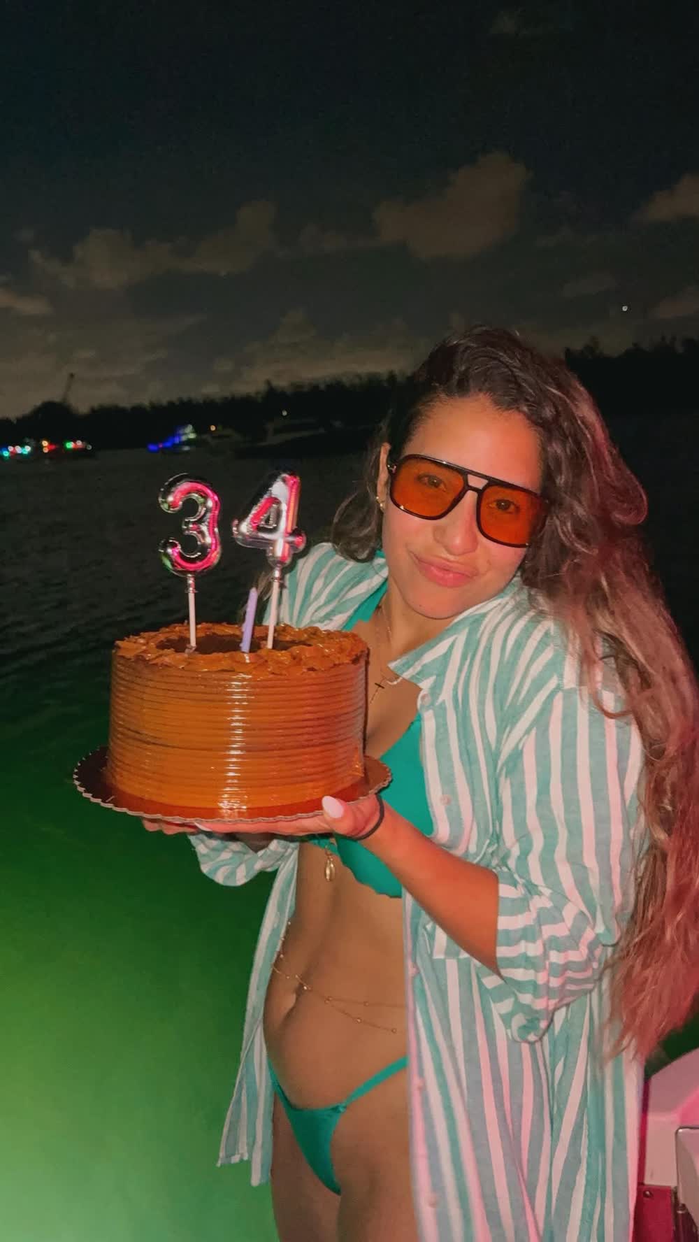 Una invitada con el bizcocho de cumpleaños y las velas de número encendidas en cubierta