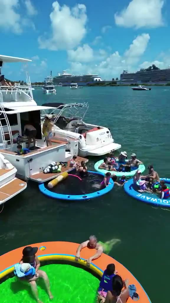 Aerial view of two LuxSea boats rafted together at the sandbar, families with small children sitting in the floating pools alongside