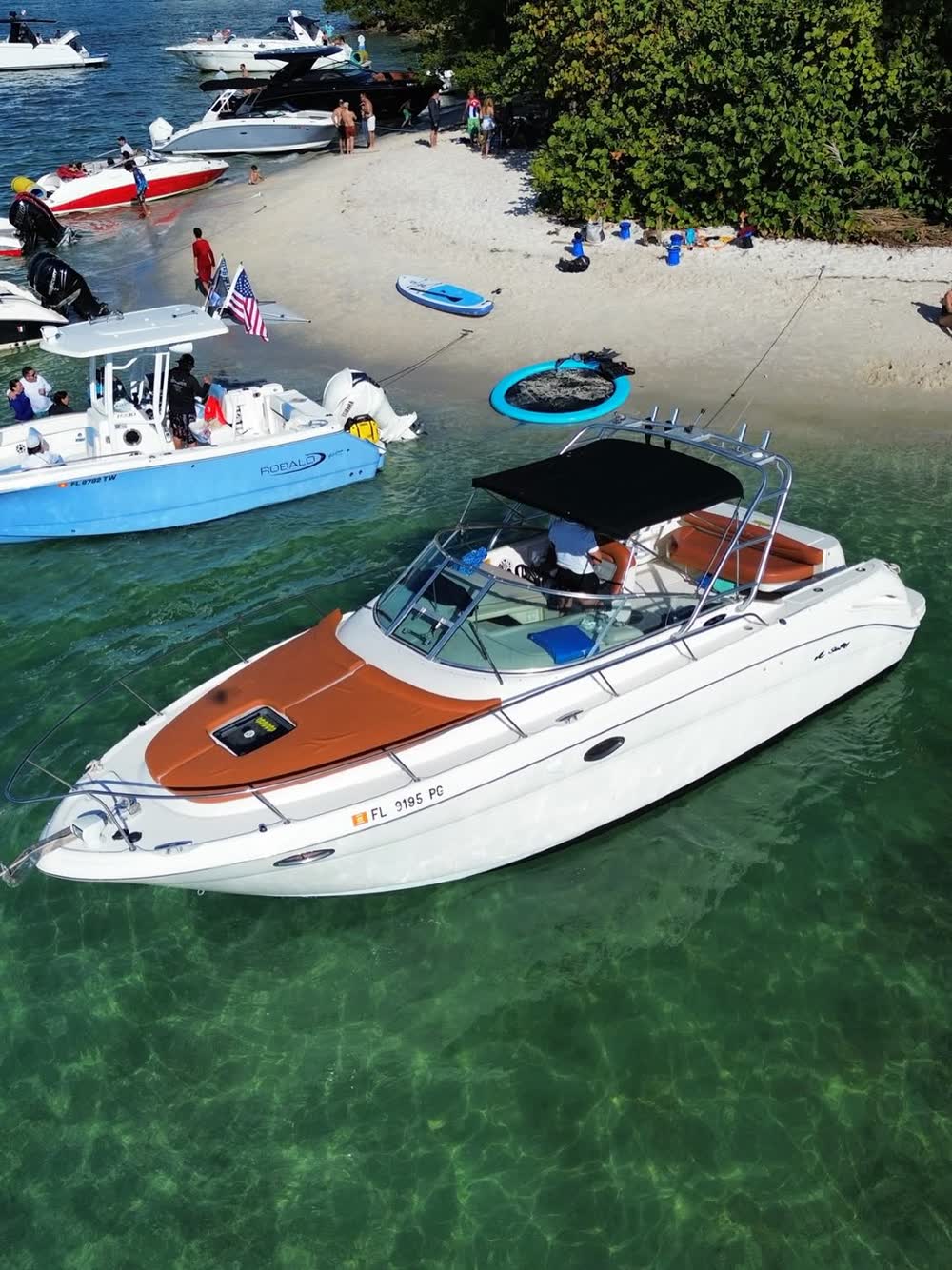 The Amberjack 32 anchored off a sandbar beach with other boats along the shore