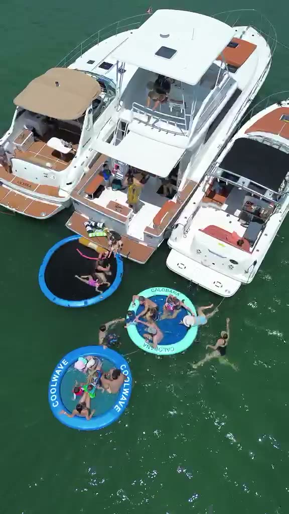 Vista aérea de tres botes de LuxSea amarrados juntos en el banco de arena de Miami, con piscinas flotantes al lado en agua verde