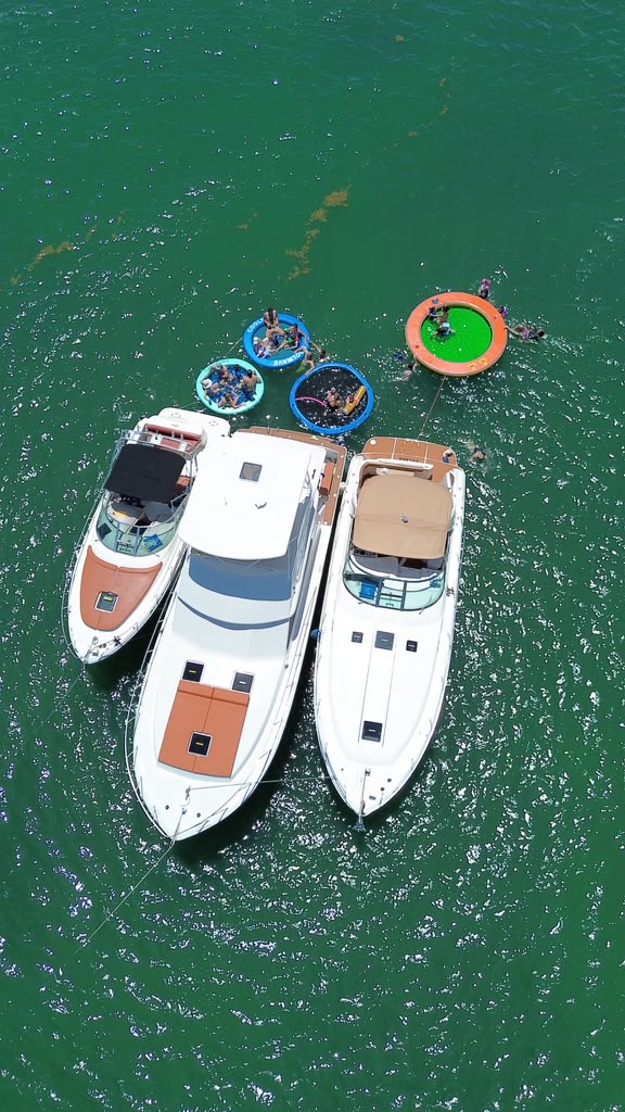 Vista aérea de los tres botes amarrados en línea, con las piscinas flotantes detrás en agua verde