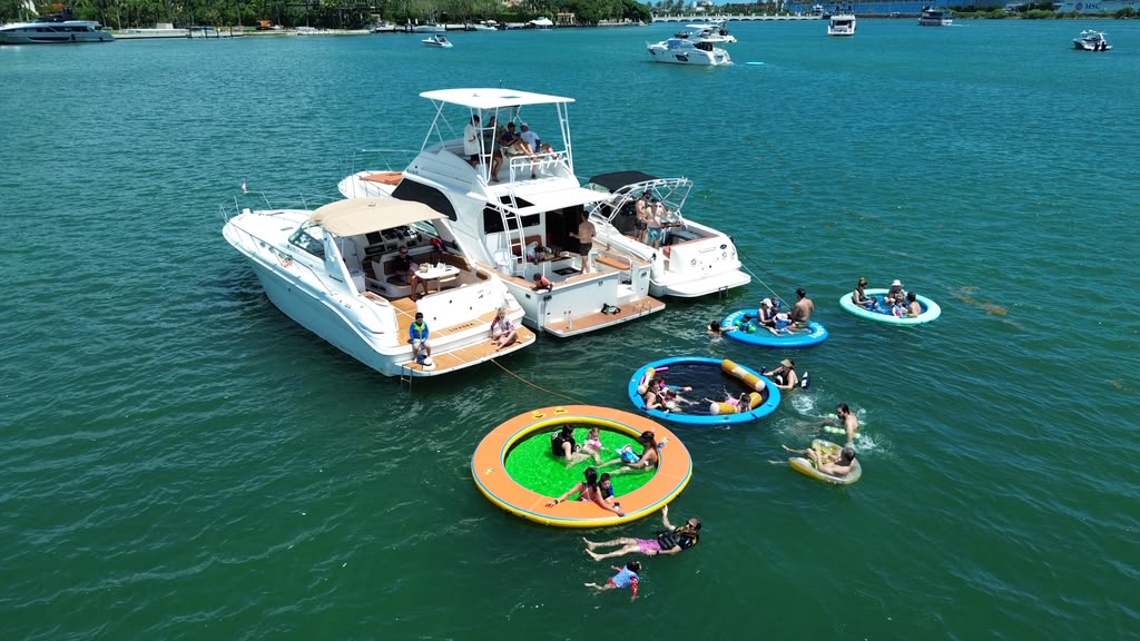 Los tres botes de LuxSea amarrados juntos en la bahía de Biscayne, con cuatro piscinas flotantes atadas a las popas y gente nadando entre ellos