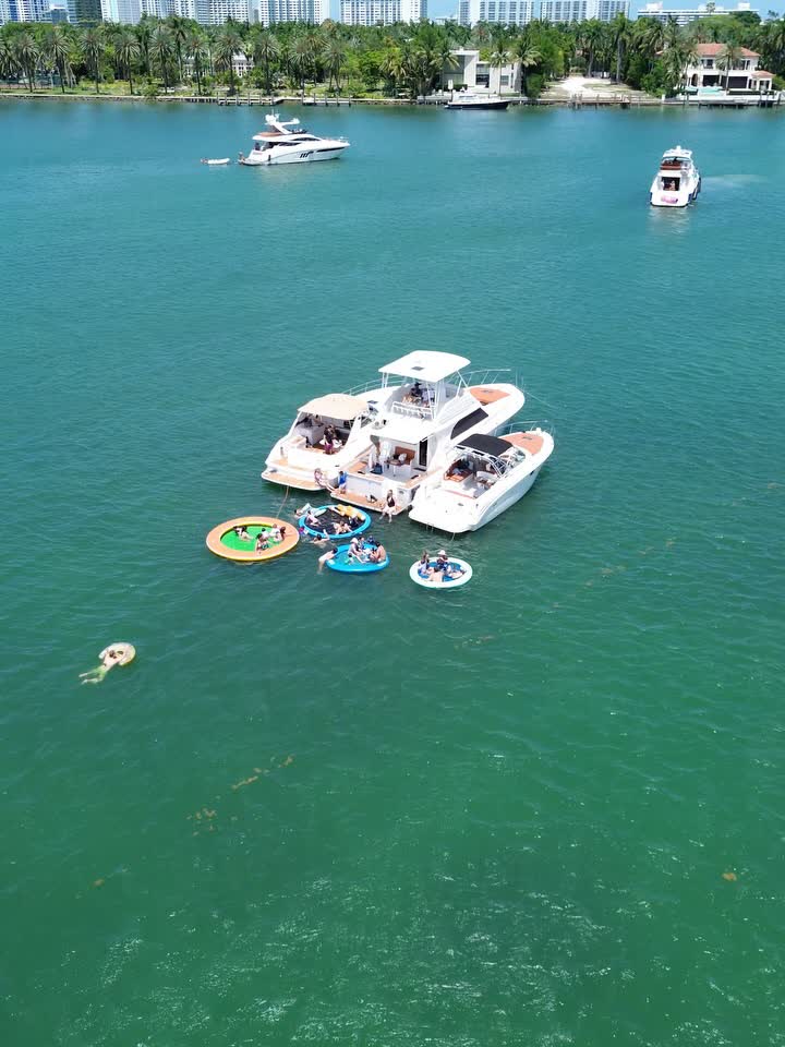 Two boats rafted together with floats out and swimmers in the shallows